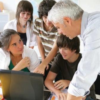 Teacher w/ students near laptop - 1 to 1