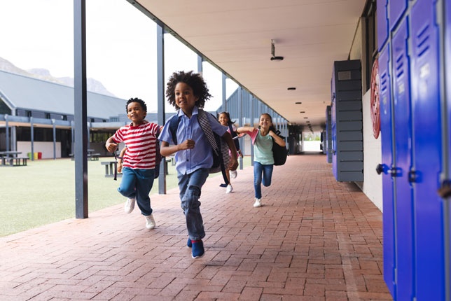 diverse group of young students running in hallway outdoors