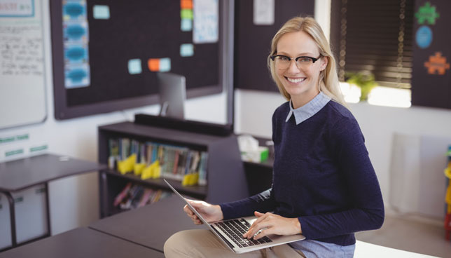 teacher using laptop in classroom