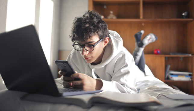 teen studying with smartphone and laptop
