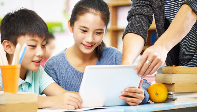 elementary schoolchildren using digital tablet in classroom 