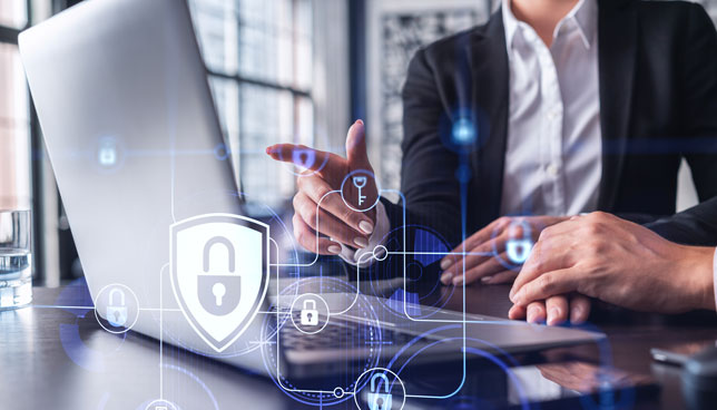 two business people working on a laptop with cybersecurity icons