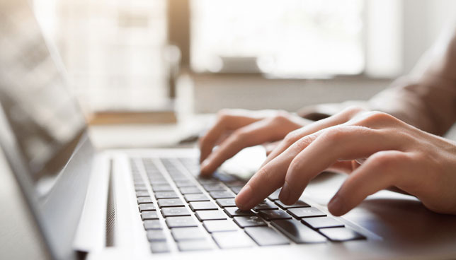 closeup of hands typing on laptop
