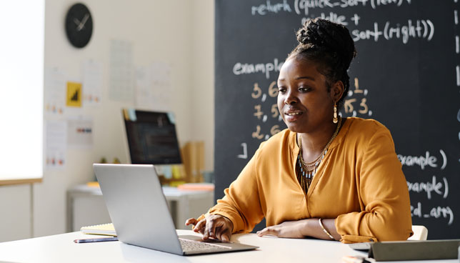 teacher working online on laptop while sitting in the classroom 