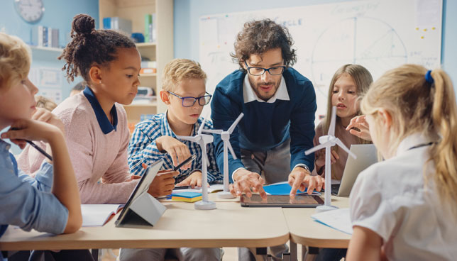 Teacher Holding Tablet Computer Explains Lesson to Young Children